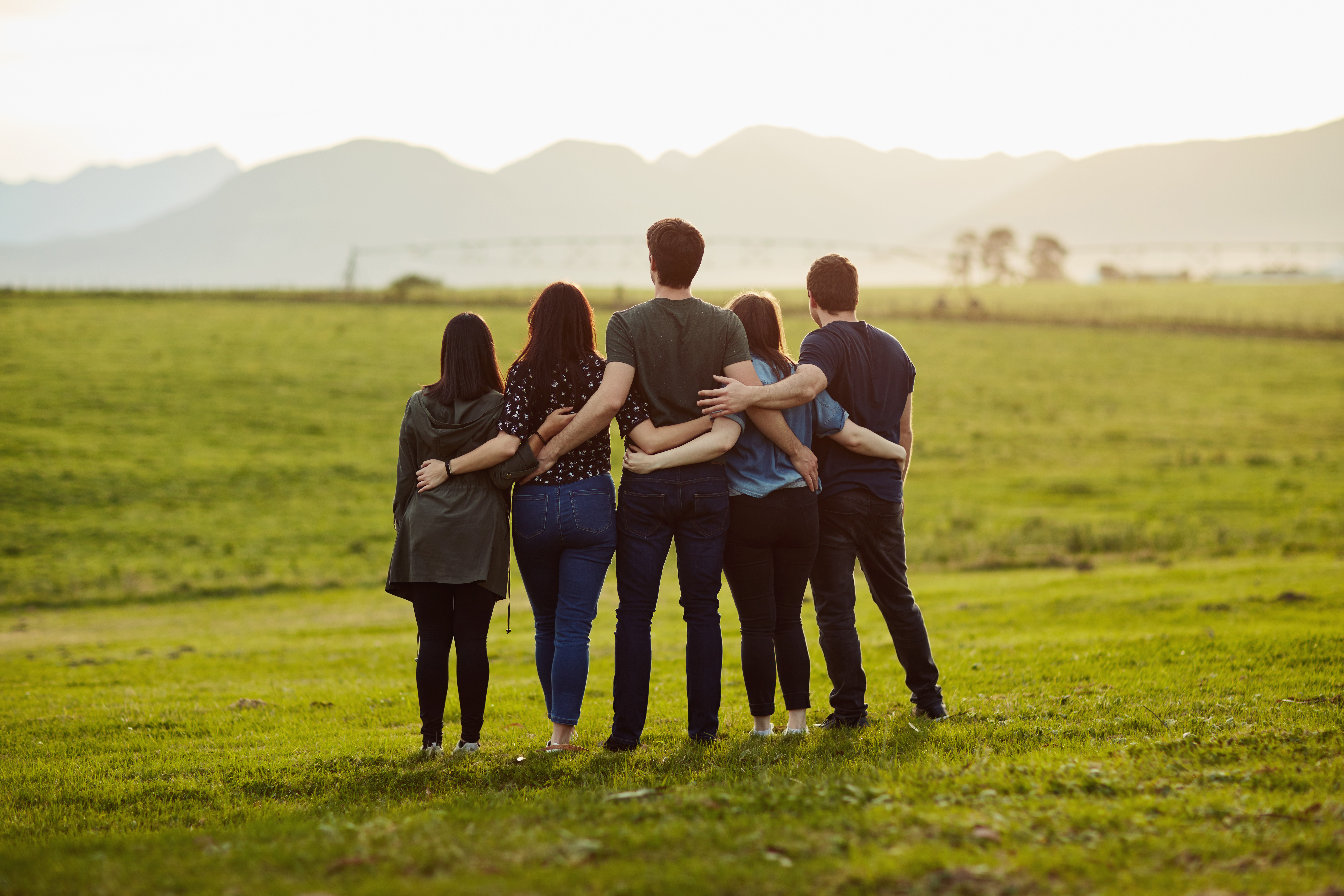 Rearview of a group of friends standing together on a open field