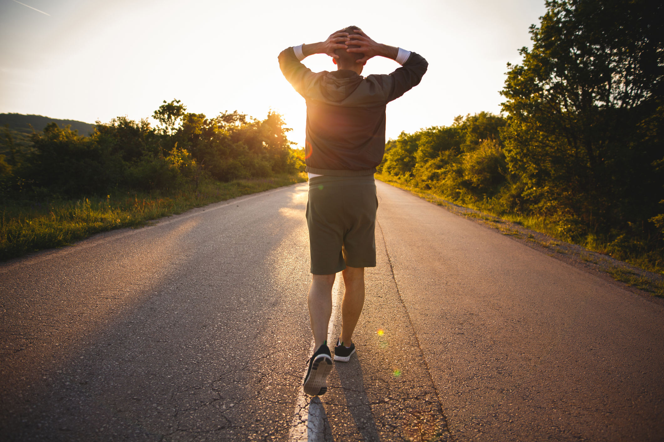 Photo of sporty man raising arms towards beautiful sunset on the road and enjoys
